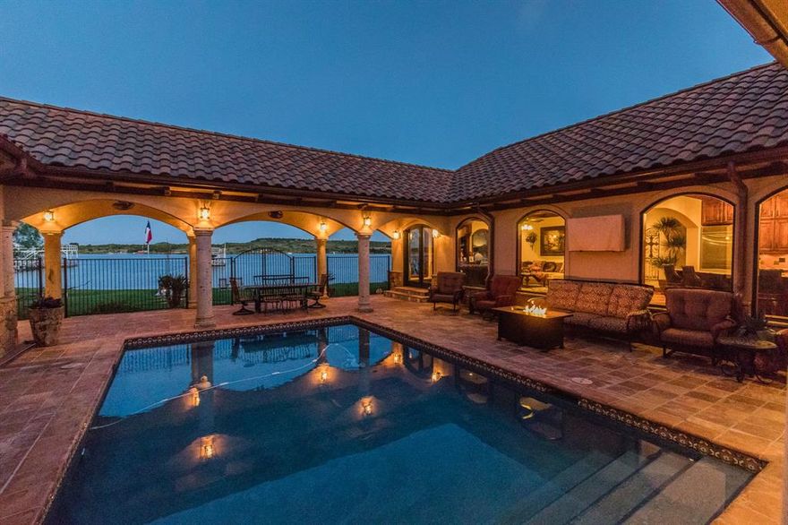 Discover your waterfront dream home at Possum Kingdom Lake! This stunning single-story residence, crafted by architect Doug Paul and constructed by Cliff Ohlert, embodies relaxation, entertainment, & unparalleled quality. Boasting an open concept design, the home features 5 bedrooms & 5 baths, ideal for hosting guests. Saltillo tile flooring spans the interior, complemented by hand-painted tiles at each doorway, knotty alder wood accents, & arched entries to every room. The expansive arched windows showcase breathtaking views, creating a warm inviting ambiance. Nestled around a central courtyard, enjoy a newly resurfaced heatable pool, multiple seating areas, outdoor ceiling fans, & inviting outdoor kitchen. This prime, unrestricted lot on the southern side of the PK Peninsula includes a 2-car garage & fully fenced landscaped yard with seamless lake access. A nearly new double-deck dock w-multiple slips, composition surface, & ample storage completes this exceptional lakeside retreat.