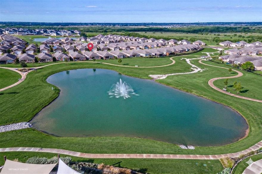 Start each day with lake views and peaceful walks along the trail just beyond your backyard, then enjoy the ease of resort-style living in this vibrant 55+ community. Life here is about choice-morning fitness classes, afternoons by the pool, or a friendly game of tennis, pickleball, or bocce. Evenings unfold on your patio with motorized shades, or gathering with neighbors at the coffee bar, food truck park, or open-air pavilion.

Sunlight fills the hardwood-floored interior, where the Living Room opens to a bright sunroom. The eat-in kitchen anchors daily life with a large island, breakfast bar, granite countertops, pendant lighting, stainless steel Whirlpool appliances, gas range, and double-door pantry- perfect for casual meals or entertaining. The sun room overlooks the lake, creating a calm retreat at day’s end.