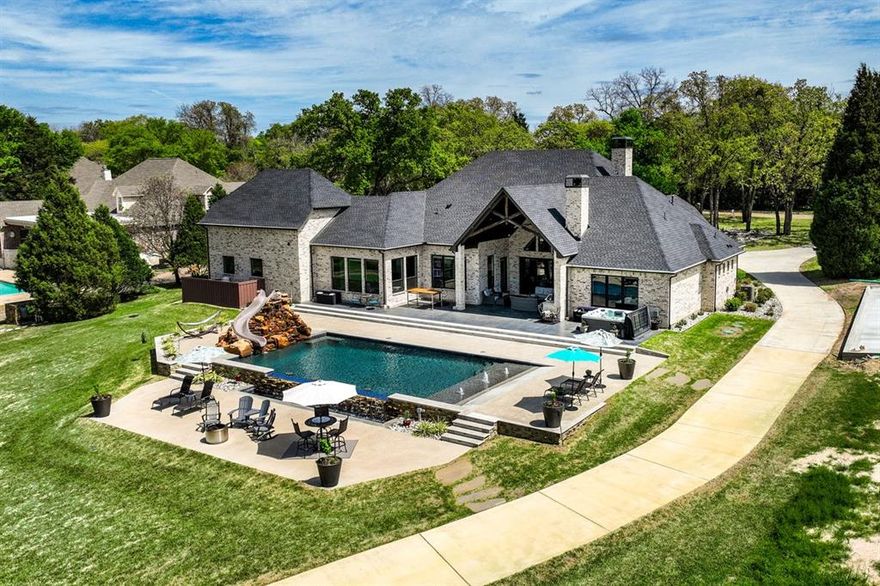 Situated among million-dollar properties, this custom-built 2022 masterpiece offers estate-sized living on 1.37 acres with 150 ft of pristine shoreline. Every detail is thoughtfully designed for both comfort and entertaining. GREAT ROOM : Vaulted, beamed ceilings, stately stone fireplace, rich wood floors, and expansive Pella sliding doors. GOURMET KITCHEN A chef's dream with granite counters, a large island for dining and serving, designer lighting, a barreled ceiling with wood inlay, propane cooking, pot filler, double ovens and microwave. PRIMARY SUITE opens to patio and features luxury spa bath, soaking tub, walk-in shower with multiple body sprays. Main level highlights include 3 guest suites , steam shower, office and second living area. A dedicated media room with half bath is located on the second level. The property's  outdoor living spaces are unmatched. Relax or entertain on the covered porch with its stone fireplace and multiple patio areas overlooking a resort style pool complete with tanning ledge, stone water feature and a slide for endless fun. The double boathouse with covered gathering area offers the perfect lakeside escape.