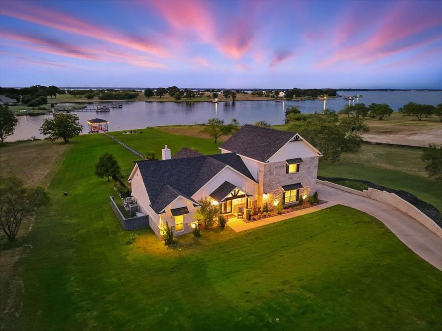 HELLO SUMMER!! Welcome to this stunning LAKEFRONT retreat on 1.1 acres, where breathtaking views surround you from the moment you arrive. A double-door entry opens to an open floor plan with soaring vaulted ceilings and a wall of windows that showcase the PEBBLETEC pool, hot tub, and sparkling lake beyond. The chef’s kitchen features a large island with gas cooktop, plenty of cabinetry, and a seamless flow into the living and dining spaces, while just beyond, the vaulted patio with a gas fireplace and full outdoor kitchen, complete with fridge, grill, and storage which creates the perfect space for entertaining. The spacious primary suite offers lake views and a spa-like bathroom with dual vanities, a soaking tub, and a separate shower with dual showerheads behind a stylish barn door. Outdoors, you’ll find a wrought-iron fenced pool area, a fire pit by the lake, and a private walkway leading to your OWN BOAT DOCK! Concrete Bulkhead also added! The home is fully encapsulated with spray foam insulation, has two AC units for year-round comfort, and includes a RAINSOFT WATER TREATMENT SYSTEM with reverse osmosis. Set in a peaceful cove  this property blends luxury, efficiency, and tranquility for the ultimate lakefront lifestyle.