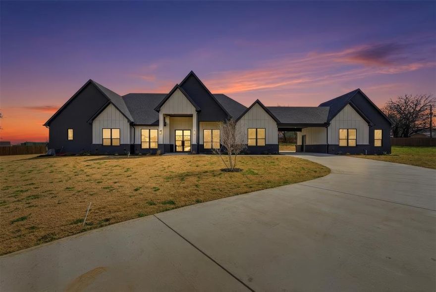 Bold modern design meets effortless livability in this brand-new custom home set on more than an acre within a gated community in highly rated Mansfield ISD. Striking black-and-white tones, warm wood accents, and clean architectural lines create a refined first impression, beginning at the double iron glass entry and continuing into expansive, light-filled interiors designed for both everyday comfort and elevated entertaining. A porte-cochère with expansive parking enhances both convenience and curb appeal, while the rear-facing two-car garage preserves the clean front elevation and thoughtful approach. The open living space flows seamlessly to a huge covered patio with an outdoor kitchen and pool, delivering true indoor-outdoor living with room to gather, relax, and unwind.
At the center of the home, a showpiece kitchen blends style and function with an oversized quartz island, custom cabinetry featuring spice racks and utensil storage, a ZLINE luxury oven and cooktop, a massive walk-in pantry, and an oversized built-in refrigerator. A window-lined dining area and private office add versatility, while the single-story layout offers multiple ensuite bedrooms and a convenient half bath near the primary suite—designed for comfort, privacy, and easy daily living without stairs.
The primary retreat provides a spa-inspired escape with dual sinks, a dedicated vanity, and a soaking tub for quiet relaxation, complemented by a large laundry room complete with cabinetry and folding space. Intentional custom craftsmanship, generous outdoor living, and the privacy of acreage complete the experience.
Blending modern elegance, functional design, and resort-style outdoor living in a secure, sought-after setting, this is a rare opportunity to own a newly built luxury home where every detail feels considered and every space feels calm, open, and ready to enjoy.