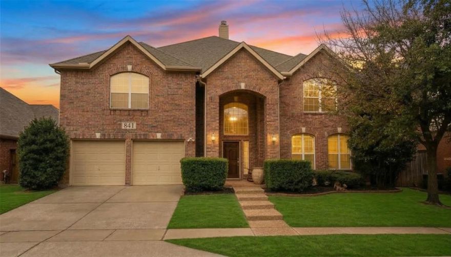 This 5-bedroom, 3.5-bath brick home offers modern luxury, great curb appeal, and landscaped lawn. The expansive open-concept interior boasts soaring ceilings and high-end finishes, creating a warm, sophisticated atmosphere ideal for both quiet evenings and grand entertaining. The interior of this home continues the theme of modern elegance with a light-filled, open-concept floor plan featuring sleek gray tile flooring and a sophisticated neutral palette. Highlights include a chef-inspired kitchen with high-gloss cabinetry and oversized kitchen island, seamlessly flowing into a dramatic living area anchored by a striking fireplace, windows from the floor to the ceiling, and an overlooking balcony. The spacious primary suite serves as a private retreat, complete with its own integrated electric fireplace set in marble-style tile and a ceiling fan for year-round comfort. Experience ultimate relaxation in the primary bath, which boasts a deep soaking tub surrounded by elegant marble-patterned tiling, a frameless glass-enclosed rainfall shower, and chic black hardware finishes. Step outside to your own private oasis, featuring a sleek custom-designed pool with integrated steps and a modern, low-profile aesthetic. The backyard retreat is accented by a stacked-stone water feature wall topped with three elegant scupper bowls, creating a tranquil atmosphere perfect for relaxation. Enclosed by a high-quality privacy fence, this space offers a sophisticated outdoor setting for entertaining or quiet afternoons by the water.