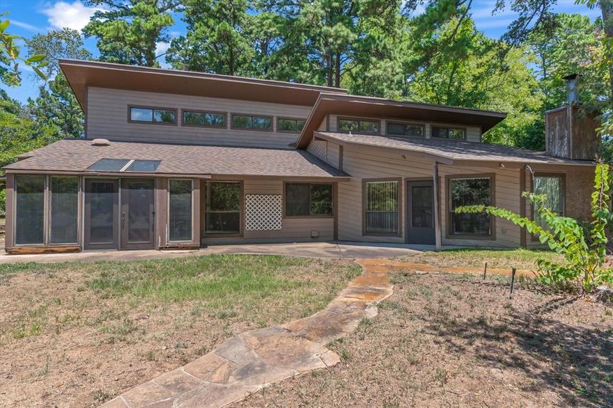 Discover this charming two-bedroom, two bath home in Hideaway Lake where midcentury modern architecture meets peaceful East Texas lake living. Just steps from the water, this open concept home features soaring vaulted ceilings, a cozy wood burning fireplace, and an inviting loft that is perfect for a home office or guest space. The primary suite includes an enclosed sunroom that is ideal for morning coffee or relaxing after a day on the lake, along with a spacious ensuite and additional room that could easily be transformed into a large walk-in closet. The kitchen offers rich wood cabinetry and abundant counter space for cooking and entertaining. A two-car garage provides room for vehicles, a workshop, or extra storage. With a little TLC and modern updates, this home could truly shine as a midcentury modern showpiece once again. Living in Hideaway Lake means enjoying twenty-seven holes of golf, three private stocked lakes, a clubhouse with bar and grill, community pool, tennis courts, parks, trails, RV and boat storage, and twenty-four-hour gated security with EMS. Families will appreciate the highly rated Lindale ISD and the convenient location near Tyler’s shopping, dining, and hospitals. Perfect as a primary residence, weekend retreat, or investment opportunity, this Hideaway Lake home offers style, potential, and a lifestyle you will love.