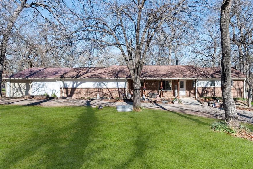 Check out this adorable 4 bedroom, 3 bath farmhouse situated on nearly 5 acres featuring two primary bedroom suites and plenty of space for horses and farm livestock. Tucked away in a secluded and private setting, this property welcomes you with a circular front drive, planter beds, and a covered front porch perfect for morning coffee and quiet country views. Inside, you’ll find a huge open living room filled with natural light from large windows overlooking the back acreage, anchored by a beautiful brick fireplace ideal for cozy family nights. The home offers a warm, updated layout with fresh interior paint in a gray and white palette and beautiful engineered luxury vinyl plank wood flooring throughout the main living areas and bedrooms. The updated farmhouse kitchen boasts butcher block countertops, subway tile backsplash, farmhouse sink, white cabinetry, stainless steel appliances, and a huge walk-in pantry. Spacious primary and secondary bedrooms provide comfortable living, while the private mother-in-law suite on the opposite end of the home includes its own living area, tile floors, updated bathroom and shower, abundant storage, and dedicated central HVAC. Additional features include a large garage workshop with roll-up door for easy access, storage and parking, private well, and a covered two-car carport. Washer, dryer, and kitchen refrigerator convey with the home. Step outside to an adorable screened-in back patio, extended patio space, and expansive cross-fenced acreage complete with chicken coops, flexible pens for goats and pigs, and open pasture ideal for horses and cows, plus a firepit perfect for outdoor gatherings. Major updates include NEW HVAC in 2024 and NEW water heater in 2024. This property offers the perfect setup for the country lifestyle you’ve been looking for. Welcome home!