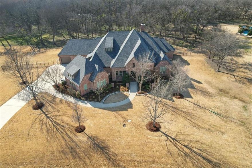 Tucked away on a private cul-de-sac in highly sought-after Lovejoy ISD, this exceptional 4,530 sq ft one-story estate offers the perfect blend of luxury, privacy, and everyday functionality on 2 beautifully landscaped acres with a tranquil, wooded backdrop.

Designed with comfort and entertaining in mind, the home features 4 spacious bedrooms and 4.5 baths. All of the secondary bedrooms offer en-suite bathrooms - ideal for both family living and hosting guests. Rich wood floors, custom built-ins, soaring cathedral ceilings, and a stunning stone fireplace create a warm, elevated atmosphere in the expansive open-concept living area.

Step outside to your own backyard retreat, complete with a sparkling pool and a covered patio featuring an outdoor fireplace and built-in grill, creating the ultimate space for year-round entertaining.

Car enthusiasts and outdoor adventurers will love the rare 5-car garage, including a fifth bay large enough to accommodate a fishing boat, plus stairs leading to extensive attic storage.

With additional living and dining spaces, a dedicated office, incredible outdoor amenities, and unmatched privacy, this home truly has it all—an extraordinary opportunity in one of North Texas’ most desirable locations.