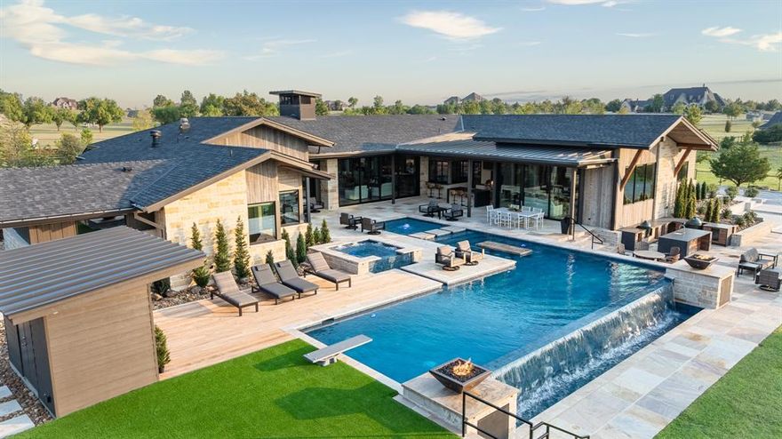 Less than an hour from Dallas, in Rockwall County—Texas’ smallest yet wealthiest county—this lakeside community draws those seeking space, privacy, and an elevated lifestyle. Set on over five acres within a gated subdivision, further secured by its own private entrance, this estate was crafted as the builder-developer’s personal residence and stands as a masterclass in Texas Modern design. Defined by clean architectural lines, organic textures, and expansive walls of glass, every detail is intentionally curated to blend sophistication with ease, offering enriched daily living and effortless entertaining.
The 5,649 SF main residence showcases a gourmet kitchen and grand living area anchored by a striking linear stone-framed firebox, where views spill seamlessly outdoors. A dedicated fitness and wellness space opens directly to fresh air and poolside vistas, creating harmony between activity and retreat. From the upper level of the 1,486 SF two-story guest house-design studio, gather next to the fireplace and enjoy sweeping views of the estate and its grounds. The property also includes a 1,497 SF garage with workshop—ideal for creativity, hosting, or collection storage.
Outdoor living unfolds across multiple gathering spaces, from expansive covered patios and full kitchens designed for celebrations to sleek lounging areas by the infinity-edge pool with in-pool bar seating. Play pickleball on your private court, watch the kids bounce on the in-ground trampoline, or wander to the private pond where casting a line offers simple joy. Take a ride by horse or ATV on trails within the subdivision. As the sun sets, gather around a fire pit nestled beneath manicured trees by the creek, sharing stories under the Texas sky.
This is more than a home—it’s a luxury lifestyle designed for connection, recreation, and retreat. With Dallas less than an hour away, every convenience is within reach while you revel in the privacy of your own sanctuary.