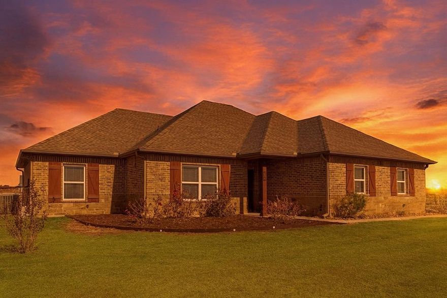 Welcome to this 4-bedroom, 2-bath brick and stone beauty perfectly set on a full acre in an highly rated school district. Nestled on a corner lot along a peaceful county road, this home offers the perfect blend of space, privacy, and small-town charm with pipe fencing enclosing the entire backyard. Step inside and fall in love with the open-concept floorplan, where the kitchen flows seamlessly into the family room, centered around a cozy wood burning fireplace. The split-bedroom layout provides comfort and privacy, while the spacious utility room offers abundant storage and cabinet space. The primary suite en-suite bath offers a double-vanity bath with jetted tub, separate tile shower, and a walk-in closet. Unwind under the covered back patio as you take in the breathtaking Texas sunsets, the perfect backdrop for grilling, entertaining, or simply relaxing after a long day. This property offers everything you’ve been searching for: acreage, charm, and convenience all wrapped up in one beautiful package. Frontier high speed internet available and no HOA, no MUD, no PID, NO CITY TAXES, just outside city limits.