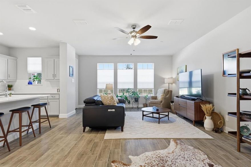 Thousands of dollars in premium upgrades you won’t find in the base models were put into this townhome that still feels brand new! From the moment you step inside, you’re greeted by gorgeous wood-look tile that flows seamlessly throughout the main level, elegant five-inch baseboards, designer paint and trim, custom top-down bottom-up blinds, and a ceiling fan that keeps the open-concept living space bright and airy. You’ll fall in love with the kitchen: sparkling 3 cm quartz countertops with sleek square edges, massive center island, crisp shaker cabinetry, brushed nickel pulls, extended walk-in pantry, overhead fridge cabinet, large subway tile backsplash, stainless steel appliances including built-in oven, drop-in cooktop and over-the-range microwave, lots of cabinets for storage, undermount single-bowl sink with pull-down faucet. An elegant wrought-iron spindle staircase leads you all the way upstairs. Your primary suite boasts nine-foot ceilings, a ceiling fan, custom top up bottom down blinds, and two walk-in closets.  Main bath with quartz and beautiful tile. The split bedrooms plan offers privacy, with both secondary bedrooms enjoying nine-foot ceilings and custom blinds, plus convenient second-floor laundry. Thoughtful upgrades continue with plush carpet over a half-inch 8-pound pad, five-panel interior doors, pre-wiring for app-controlled security and smart features, freeze-resistant PEX plumbing, fire sprinklers, an energy-efficient Trane HVAC system for lower utility bills, an extended rear walkway, and a rear door with built-in blinds. The low-maintenance lifestyle here is unbeatable, the HOA covers all exterior maintenance including the roof, mowing, watering, and landscaping, freeing up your weekends and often qualifying owners for lower insurance rates. Located just minutes from top-rated KISD, shopping, and easy commute to the DFW metroplex.