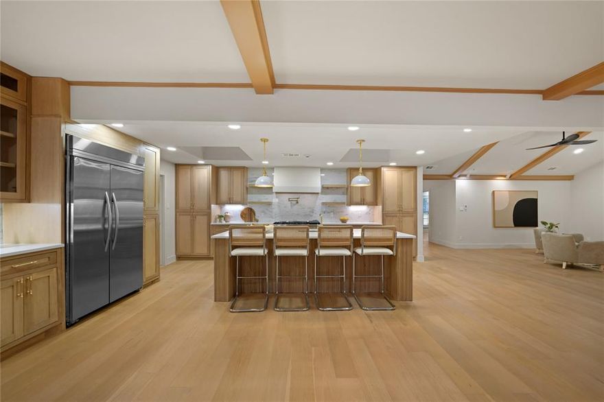 Exceptionally renovated and magazine-worthy, this mid-century modern 3,728 SF residence is a true standout. Located at 7736 Woodstone Lane, the home offers 5 bedrooms plus an office, 3.5 baths, and a private 0.32-acre lot in Far North Dallas. Thoughtfully redesigned with top-tier finishes and modern upgrades, this open concept family home blends style, function, and comfort at every turn. Step inside to an open-concept layout featuring a cozy fireplace with Venetian plaster surround, a chic wet bar, designer lighting, and seamless flow between the living, dining, and kitchen areas. The gourmet kitchen is a true showpiece, offering expensive custom-built white oak inset-style cabinetry, quartz countertops with dolomite backsplash, a 10-ft eat-in island, and all-new premium SS appliances. The spacious primary suite includes a large walk-in closet and a stunning ensuite bathroom featuring Bedrosians & Terrazzo tile, a standalone soaking tub, an oversized double-rain shower, and a dual vanity. Two additional bedrooms share a beautifully upgraded Jack-and-Jill bath with a walk-in shower, while two more bedrooms share a sleek hall bathroom with tub - ideal for guests and conveniently located near the kitchen area. A spacious office is positioned near the front entry. Beautiful engineered white oak hardwood flooring flows throughout the home, complemented by designer tile in baths. Step outside to a private and spacious backyard featuring lush landscape, new sod, a pergola and an outdoor kitchen - perfect for relaxing or entertaining. The oversized driveway offers parking for up to six cars, plus a two-car garage. Conveniently located near premier shopping, dining, and entertainment with quick access to PGBT and DNT, this home offers exceptional convenience to all your favorite Dallas destinations. This home offers not just a place to live, but a lifestyle. Schedule your tour today!