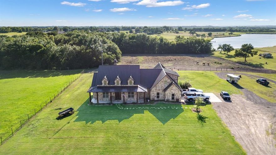 This stunning gated lakefront estate is situated on 3.6 acres in the highly desirable Rockwall ISD, offering a rare opportunity to own a one-of-a-kind ranch-style stone home with a fully equipped barndominium and horse facilities. Discover the perfect blend of luxury, privacy, and country living just minutes from downtown Rockwall and I-30. Step through custom wrought-iron double doors into an interior rich with charm and craftsmanship—featuring hand-scraped hardwood floors, travertine stone tile & a full masonry fireplace perfect for cozy winter nights. 
The open-concept floor plan is ideal for entertaining, showcasing a chef’s kitchen with commercial-grade stainless steel appliances, granite countertops, and ample prep space.
The luxurious primary suite boasts an oversized walk-in closet with direct access to the laundry room, a spa-inspired bathroom with a slate walk-in shower & a copper clawfoot tub. Two additional downstairs bedrooms share a stylish Jack-and-Jill bath with custom whiskey barrel sinks & large walk-in closets. Upstairs, you'll find a spacious second master suite or potential game room,media room with a private full bath & walk-in closet.
Enjoy plantation shutters, high-end finishes throughout and panoramic views of the private lake and surrounding pastures from the covered back patio. 
ALSO AVAILABLE AND SOLD SEPARATELY IS MLS 21099578: An exceptional 2000+ SF barndominium featuring: living quarters with private entry, large workshop area, three premium horse stalls with windows. Designed for comfort, privacy, and multi-use living. Perfect for equestrian lovers, hobbyists, or those seeking a peaceful retreat with luxury amenities and room to grow.