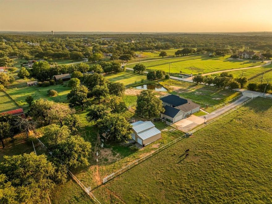 Welcome to your storybook country escape featuring 4 beds plus an office, 3 full baths and 3 living areas (one would make the perfect mother-in-law set up). Where the sky stretches wide, animals roam happily & there is space to breathe. Nestled on 2.152 breathtaking, tree-filled acres in Denton County, with 1.652 acres AG exempt, this enchanting property represents not just living, but belonging. Whether you're a hobby farmer, equestrian, or simply craving peace, this home offers the perfect blend of modern farmhouse living & rural amenities. Be greeted by a covered front porch and pond, made for slow sips, sunsets & stories shared. The entrance is flanked by an office with French doors & spacious dining with built-ins. Plantation shutters & farmhouse-inspired luxury vinyl floors add charm & elegance. Watch animals run free through the farmhouse sink window in the kitchen that boasts granite, stainless appliances, a pot filler, appliance garage, double ovens (conv. microwave), custom pull-out pantry & coffee bar+insta-hot water. Main living frames the unforgettable, panoramic views of the back patio & entertaining space with a built-in prep station for your grill, made for cookouts & star-lit conversations. Primary bed features an oversized tiled shower, 2 granite vanities & a two-compartment walk-in closet, one can double as a storm shelter. Laundry with sink & cabinets tucked behind a barn door. This home has a private wing that includes another living, full bath with walk-in shower, walk-in closet & access to garage, backyard & drop zone area. While currently open, it’s framed for a future privacy wall, should separation be desired which would create the perfect MIL suite. 26x24 epoxy-finished garage has oversized 8 ft. door. Land is fully pipe fenced & features a 31x40 barn with 4 stalls, 1 outfitted for animals. Barn includes full electric, 220 outlet, stained concrete floors, 18 ft. overhead door & drive-through access for vehicles 30ft. long & 18ft. high.