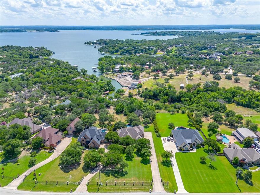 Luxurious ranch style home set upon over an acre and a half on Eagle Mountain Lake! This elegant 3-bedroom, 3.5-bathroom ranch-style residence is a masterpiece of comfort and style, designed for those who appreciate the finer things in life. Upon entering, you'll be greeted by vaulted ceilings that elevate the spacious living areas adorned with exquisite travertine and wood flooring, and built in cabinets throughout. The gourmet island kitchen, with its granite countertops and gorgeous wood cabinets, is a chef's delight. The office equipped with built-in cabinets is ideal for working from home. For those who revel in entertainment, this home is your haven. A game room with wet bar and a media room ensure endless amusement. Step outside to find your private paradise: a saltwater stone pool with a spa and waterfall, enveloped by a sprawling patio. Under a charming cedar arbor, the outdoor kitchen with a commercial grill awaits your culinary creations, while the fire pit and gazebo beckon for tranquil evenings under the stars. The master suite offers a Greek-style marble sanctuary with his and hers sinks and a massive walk-in closet —a perfect retreat at day's end. Approximately 25 ft of water frontage with lake access!