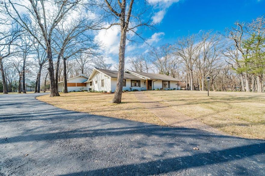 Privately tucked along a quiet one-lane drive beneath a canopy of mature post oaks, this fully renovated 4-bedroom, 1972 ranch-style residence offers a rare blend of architectural character, refined modern finishes, and peaceful seclusion, just ninety minutes from the Dallas metroplex.

The home has been thoughtfully reimagined with white oak flooring, custom millwork, and curated designer lighting throughout. The open living and dining spaces center around a stunning chef’s kitchen featuring marble and granite surfaces, custom cabinetry, premium Fisher & Paykel appliances, a Zephyr wine and beverage refrigerator, and an oversized island ideal for gathering and entertaining.

Multiple living areas provide exceptional flexibility, including a dramatic main living room with vaulted ceiling and exposed beam detail, a secondary living space with warm wood ceiling treatment, and a private flex room that easily serves as a fourth bedroom or home office. The primary suite serves as a serene retreat with a spa-inspired shower featuring Kohler fixtures and refined stone finishes. A secondary bath showcases a Kohler deep soaking tub with marble tile, as well as a third with handmade Moroccan Zellige tile, a design moment for the home.

Outdoor living includes a beautifully designed stone patio that connects seamlessly to the main living areas, and the property is enveloped by natural privacy and mature landscaping, creating a peaceful, retreat-like atmosphere rarely found so close to town.

Additional highlights include spray-foam attic insulation for energy efficiency, Therma-Tru exterior doors, Emtek hardware, elevated secondary baths, a thoughtfully designed laundry space, and consistent, high-quality finish selections throughout.

A timeless property where craftsmanship, comfort, and setting converge, offering understated luxury in one of Sulphur Springs’ most desirable and private enclaves.

Agent is also the homeowner.
