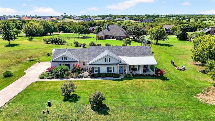 This beautiful hilltop home sits on over an acre, with mature trees lining the west side to provide privacy and a beautifully landscaped yard. Inside, a welcoming office opens into a grand open-concept layout featuring a spacious kitchen, dining area, and living room—perfect for everyday living and entertaining. The kitchen shines with a large eat-in island, abundant cabinetry, open shelving, and a huge walk-in pantry, while the shiplap ceiling and exposed beam add timeless character. An enclosed back porch offers flexible space—ideal for guests, hobbies, or a bonus room to fit your needs.
You’ll love the oversized laundry room, complete with a sink, ample cabinetry, and convenient mudroom features coming in from the garage. The bedroom wing includes two generously sized secondary bedrooms and a hall bath, while the primary suite serves as a private retreat with a sitting area, dual dressing spaces, a luxurious bath, and a spacious walk-in closet. Step outside to enjoy space for gardening, a nice-sized shed, and plenty of room to relax or entertain. This home blends comfort, charm, and functionality in a peaceful setting—an opportunity you don’t want to miss!