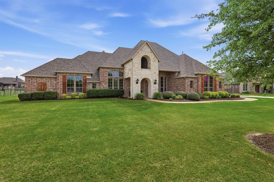 Located on a full acre in one of Lucas’ most sought-after communities. This is a rare opportunity within highly acclaimed Lovejoy ISD. Combining privacy, space, and proximity to key North Texas destinations, this property delivers a more intentional alternative to traditional suburban living.
Inside it immediately feels different. Soaring vaulted ceilings with hand-hewn wood beams, a floor-to-ceiling stone fireplace, and an open-concept great room create a space that lives as beautifully as it entertains. The chef’s kitchen is designed to impress with double granite islands, custom knotty alder cabinetry, gas cooktop, double ovens, and a stone backsplash, complemented by thoughtful details like a pull-out spice rack, concealed mixer station, and a high-tech sink. The formal dining room, set beneath an elegant rotunda ceiling, comfortably hosts 12 or more.
The home is built for today’s lifestyle. A private office plus a hidden workspace offers flexibility for hybrid work, while the first-floor media room allows for seamless entertaining without disrupting the flow of the home. The primary suite provides a true retreat with a spa-inspired ensuite featuring dual shower heads, while the upstairs guest suite with a private bath is ideal for extended stays, in-laws, or teens seeking their own space.
Outside is where this home separates itself. Set on a full acre, the backyard is designed for both everyday living and elevated entertaining, featuring a pool, spa, outdoor kitchen, covered living area, and a motorized drop-down TV that transforms the space into a true resort-style experience.
Comparable homes of this scale and quality in nearby markets like Frisco and Plano often command significantly higher prices, making 406 Spurgin Rd not just a home, but a strategic lifestyle investment in one of North Texas’ most desirable areas.