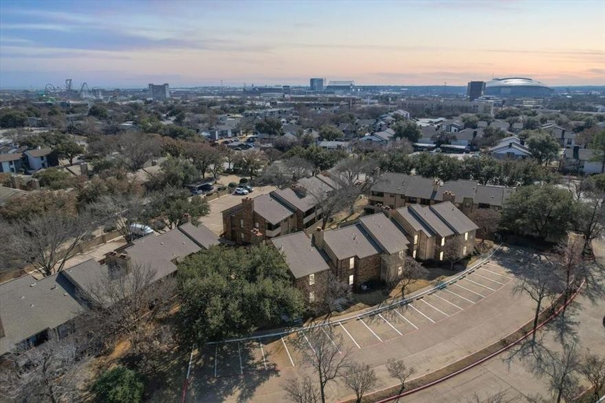 Top-floor condo in the gated Cloisters Condominiums community just walking distance to Arlington’s Entertainment District! This 2-bedroom, 2-bath unit offers a functional split layout with updated vinyl flooring throughout the main living areas and ceramic tile in both bathrooms. The spacious primary suite features a large ensuite bath with dual sinks and an extended vanity. The living room is anchored by a cozy wood-burning fireplace and flows seamlessly into the dining area and kitchen, creating an inviting space for relaxing or entertaining. Enjoy your private, covered back balcony with exterior storage—perfect for morning coffee or an evening wind-down. Recent updates include a newer HVAC system, new attic insulation, and a newer water heater for added efficiency and peace of mind. The unit comes complete with refrigerator, over-the-range microwave, washer, and dryer. Two assigned parking spaces are located directly in front of the unit, and the building sits very close to the gated entrance off Lamar for convenient access. HOA covers water, trash, and sewer, adding value and simplicity to ownership. Residents enjoy resort-style amenities including on-site property management, three illuminated swimming pools, lighted tennis courts, racquetball courts, clubhouse, full workout facility, hot tub, and sauna. Minutes from Texas Live!, AT&T Stadium, Globe Life Field, Choctaw Stadium, Six Flags, Hurricane Harbor, and more, with walkable access to shopping and dining including Whole Foods Market, Torchy’s Tacos, Starbucks, and additional retail. Quick access to DFW Airport and a central location between Dallas and Fort Worth make this an excellent primary residence.