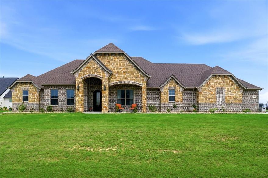 Welcome to this custom one story built by Couto Homes located in the highly coveted Bella Crossing community. A barrel ceiling greets you upon entry and leads you into the fabulous great room. This living space features a floor to ceiling stone gas fireplace, luxury vinyl plank flooring throughout, extensive millwork complemented by an intentional design. The kitchen is a chef’s delight with quartz countertops, pot filler, wine fridge, soft close cabinetry, gas cooktop, and double ovens. The large primary suite is positioned for privacy and boasts a true spa-like retreat with dual vanities, an oversized custom wet room complete with shower and a luxurious freestanding soaking tub. The primary closet will not disappoint and flows nicely to the generous sized laundry room that includes space for an additional fridge and has a large pet shower. The ADA compliant secondary primary suite is uniquely located in the home for privacy and includes an ensuite bath with walk-in shower. Two additional bedrooms share a jack and jill bath. The fifth bedroom also has an ensuite bath. There is a private study with a groin vaulted ceiling. The flex room is currently being used as a game room, with a closet, it could easily be a sixth bedroom or simply a secondary living space. The outdoor living space includes a gas fireplace for those cool evenings, a built-in grill and sink. With just over an acre there is plenty of room for a pool. The four car garage includes epoxy flooring and plenty of storage space.