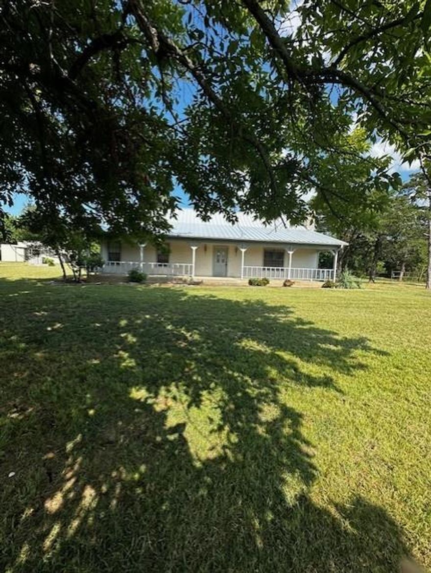 Looking for a place to enjoy country living with room for horses or other animals, then take a look at this one and a half story ranch style home built in 1990, on 7 fenced & cross fenced acres. The covered front & back porches and the large front yard are perfect for spending time and entertaining. As you enter through the front door, the vaulted beamed ceiling is first enhanced by the stairway leading to a bedroom, then across the room by the gas log fireplace sitting on a stone base with a floor to ceiling stone chimney centered between two windows. The kitchen and dining area has ample space for cooking or sitting at the table or breakfast bar with family and friends. As you leave the kitchen, there is an under the staircase closet. The primary and 2nd bedrooms are down the hall. Primary has double closets and a primary bathroom with a tub shower combo. A 2nd bedroom has a nice closet and 2 windows for natural lighting. An additional bathroom is located in the same area and has a walk-in shower stall. The 3rd bedroom is located upstairs with a window looking south toward the barn. The laundry room has a closet, built in ironing board, washer dryer hookups, & a place for an upright freezer, as well as a door leading back outside to the detached 2 car garage sitting across the driveway. A storage shed and carport are also located in the yard. The 4-stall barn with an extra wide hallway, has electric and water, a tack room, a hay storage area built off the north side, and a fenced lot on the south side. Two loafing sheds provides shelter for your animals out in the pasture. Schedule your showing today and take a look at this home to appreciate all it has to offer. It is being sold as is but is livable now. Vision your own personal touch when viewing. All info deemed accurate, buyer & buyer representative to verify all information. Dianna Whitlock, listing agent, is a Texas Licensed Real Estate Agent & has an ownership interest in this property.