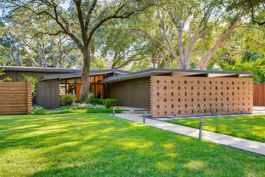 William E. Benson designed midcentury modern home in sought after Old Preston Hollow location. You are guaranteed to fall in love upon driving up to this stunning piece of Mid Century Modern history that has been meticulously restored and renovated over the years to marry the period details with modern amenities. The towering trees, expansive lawn and lush landscaping frame the one story home while the architectural detail of the brick work, low slung roof lines and bright entry door draw your eyes in! Walking up to the home, the flagstone path leads you from the outside in where you will be greeted by period African Korina wood built-ins, solid teak flooring, floor to ceiling windows and a stunning gas fireplace with original 1x1 glass tiles. The expanded and renovated kitchen is the perfect place to cook and gather featuring custom cabinetry, professional series Jenn Air appliances, quartz counters and a large center island. There are 2 light filled living areas, both featuring beautiful period built-in cabinetry and large windows overlooking the rear yard. The bedroom wing of the home includes a serene primary retreat with a fully renovated bath, restored cabinetry and closets, and an original built-in vanity area. The 2 secondary bedrooms share the updated hall bath with period accents and each is highlighted by custom built-ins and cabinetry. Step outside to the rear yard and you will immediately feel as though you are no longer in Dallas either sitting by the renovated diving pool, on the Ipe deckor walking through the mature landscaping surrounding the entire home. A sign of the style, there are 3 large carports, each with abundant storage space in addition to a large drive for extra parking. Added highlights of this home include original Lightolier fixtures, mosquito misting system, Lutron lighting and interior-exterior Sonos system. This home is a must see for the Mid Century Modern home buyer!