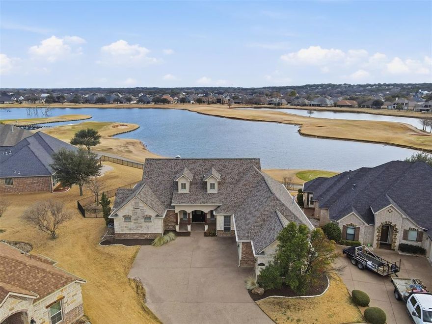 Located just off the 15th tee in the gated community of Harbor Lakes, this custom-designed home offers golf course and pond views paired with thoughtful construction and high-quality finishes. Set in Granbury, the property combines privacy with convenient access to local shopping, dining, and the historic square.

Inside, rich hardwood flooring with custom accent borders anchors the family room, while tall ceilings and arched doorways enhance the open feel. The layout flows easily into a spacious kitchen featuring granite countertops, a built-in refrigerator, dual ovens, built-in microwave, gas cooktop, and a large eat-in island with bar seating. A built-in desk and dedicated coffee bar add everyday convenience.

The primary suite is generously sized, offering space for a sitting area and capturing views of the pool and pond. The en-suite bath includes a jetted tub, separate tiled shower, split vanities, step-in tub, and a large walk-in closet.

Designed with accessibility in mind, the home features oversized hallways and wheelchair-friendly access points. A half bath serves guests, and the split-bedroom arrangement adds privacy.

Outdoors, the backyard is designed for gathering and relaxation. The covered patio includes a gas fireplace and a fully equipped outdoor kitchen with grill, side burner, and sink. The in-ground pool and spa overlook the pond and golf course, creating a peaceful setting with open views.

Additional highlights include a three-car garage with space for a golf cart and a location within a gated community that offers added privacy and controlled access. With quality finishes, scenic surroundings, and a layout built for both comfort and entertaining, this Harbor Lakes home offers an elevated lifestyle in one of Granbury’s established golf course neighborhoods.
