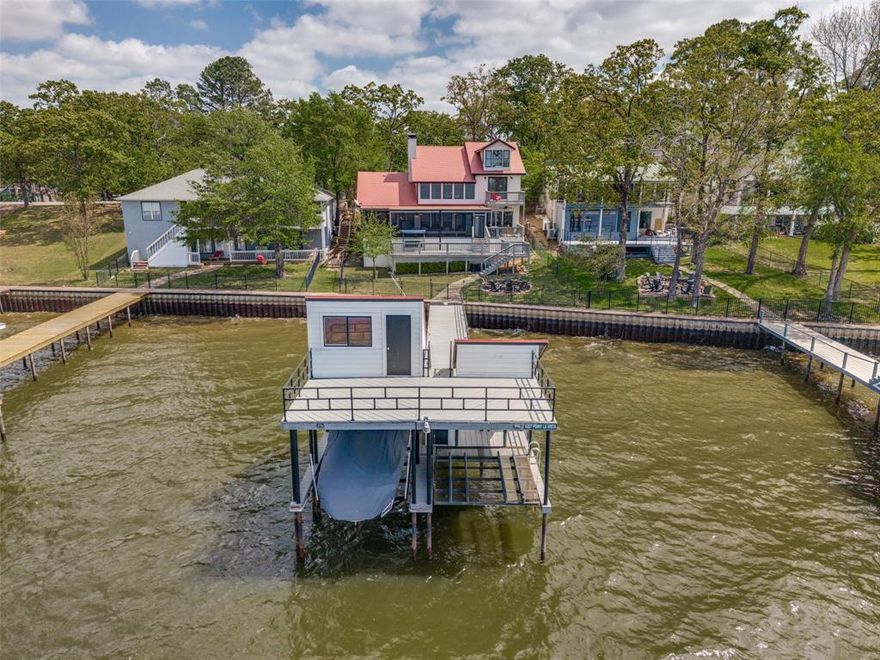 Stunning Modern Lodge, WATERFRONT home, with amazing views and DEEP WATER for boating! This is the perfect home to enjoy effortless weekends and create unforgettable memories of peaceful lake living. Enjoy evenings on beautiful oversized decks, eat dinner on a large screened in patio and you have amble room on the open air deck for grilling and lounging. The back yard has a firepit for gathering and is fenced for pets and privacy. Walking down the dock to the boat house you will find an all electric boat lift for a boat and one for two jet skis. On the boat house there is an upper deck for sun bathing and an additional storage room for boating supplies. Inside the main house,  there is plenty of space for everyone. With an open floorplan and soaring ceilings in the Living room that boast a large stone fireplace. Beams of natural light shine thru large windows to give you amazing views of the lake and the sunset. The gourmet kitchen has granite counter tops, two center islands and an eat in dinning area. The utility room and pantry are quite large and there is an additional storage closet as well. The kitchen frig will convey. Retreat to the master suite with ensuite bath, jacuzzi tub, fireplace and walk in closet . Step out of the sliding glass doors onto the patio and enjoy the view. A Large family is no problem with 2 guest bedrooms, a full bath and a patio on the second floor . And You have additional sleeping in the Bunk beds that are located on the third floor flex room. No need to worry about parking, there is a two car garage, concrete driveway and additional gravel parking facing the home. This home has an extensive, must see, update list and is in move in condition!! The furniture is negotiable and the boat is for Sale. Both will be handled on a Non-Realty addenda. The community offers access to a community boat ramp, pool and tennis courts. If you are looking for luxury lake living, this home is a dream come true.