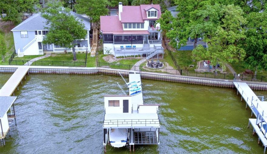 Stunning Modern Lodge, WATERFRONT home, with amazing views and DEEP WATER for boating! This is the perfect home to enjoy effortless weekends and create unforgettable memories of peaceful lake living. Enjoy evenings on beautiful oversized decks, eat dinner on a large screened in patio and you have amble room on the open air deck for grilling and lounging. The back yard has a firepit for gathering and is fenced for pets and privacy. Walking down the dock to the boat house you will find an all electric boat lift for a boat and one for two jet skis. On the boat house there is an upper deck for sun bathing and an additional storage room for boating supplies. Inside the main house,  there is plenty of space for everyone. With an open floorplan and soaring ceilings in the Living room that boast a large stone fireplace. Beams of natural light shine thru large windows to give you amazing views of the lake and the sunset. The gourmet kitchen has granite counter tops, two center islands and an eat in dinning area. The utility room and pantry are quite large and there is an additional storage closet as well. The kitchen frig will convey. Retreat to the master suite with ensuite bath, jacuzzi tub, fireplace and walk in closet . Step out of the sliding glass doors onto the patio and enjoy the view. A Large family is no problem with 2 guest bedrooms, a full bath and a patio on the second floor . And You have additional sleeping in the Bunk beds that are located on the third floor flex room. No need to worry about parking, there is a two car garage, concrete driveway and additional gravel parking facing the home. This home has an extensive, must see, update list and is in move in condition!! The furniture is negotiable and the boat is for Sale. Both will be handled on a Non-Realty addenda. The community offers access to a community boat ramp, pool and tennis courts. If you are looking for luxury lake living, this home is a dream come true.