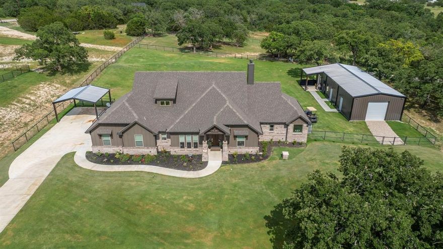 Stunning Country Home with Party Barn on 2 Acres in North Parker County, TX. This new and highly upgraded home sits on 2 pristine acres, surrounded by mature Post Oak trees. Great curb appeal and a long driveway set back from the street, this property offers both privacy and charm. Step inside to a spacious interior featuring an open floor plan, ideal for entertaining and everyday living. Just off the entryway is a dedicated office, perfect for remote work or study. The main living area has multiple windows that overlook the backyard and bring in abundant natural light. The thoughtfully designed split floorplan includes 3 bedrooms and 3 full bathrooms, allowing each bedroom to enjoy its own private bath. The home has been extensively updated in the past year with modern touches throughout, including a whole-home water filtration system, reverse osmosis at the kitchen sink, new built-in shelving, updated lighting, and updated cabinet hardware across the home. A major selling point is the massive party barn and shop space that adds an additional 1,000 square feet of heated and cooled living area complete with a secondary full kitchen and half bath, making it ideal for hosting guests, events, or creating a guest suite or home gym. There’s also a 20x25 workshop attached to the barn, on top of the houses already oversized two-car garage and two-car carport. Step outside and enjoy one of the two large porches overlooking 1.2 acres of fresh sod that has been laid, supported by a full sprinkler system covering more than an acre in both the front and backyard. The fully fenced and cross-fenced yard includes custom metal pipe fencing and gates in both the front and backyard perfect for kids, pets, or livestock. Whether you have horses or farm animals, the setup is ready for you.  At the very back of the property there are huge Post Oaks, and a wet weather creek for your kids to explore! This rare chance to get into a turn-key property with all the extras already there!