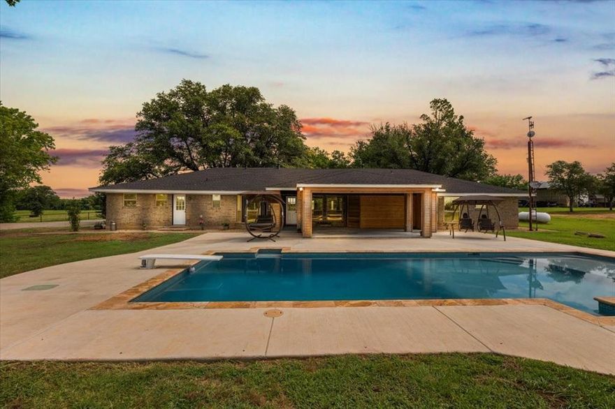 This incredible property features a guest house, pool, stock tank, barn, shop, and RV storage, all set on 38 acres of lush Coastal Bermuda grass, averaging 65 round bales per cut. Tucked less than a mile off Highway 199 in a peaceful and prime location, the main home offers 3 bedrooms, 2 baths, and 2,540 sq. ft. of beautifully, remodeled living space with wood tile floors, new plumbing and windows, an open concept design, granite countertops, stainless steel appliances, and vaulted ceilings with large beams framing views of the pool and the 7-acre stock tank. The 1,100 sq. ft. guest house includes 2 bedrooms, 1 bath, a garage, and new HVAC. The 60x60 barn is fully equipped with cattle pens, feed troughs, a squeeze chute, electricity, and water. The 40x50 RV storage has 2 50-AMP RV hook-ups, solar panels and a 20x40 awning. A second 25x30 shop includes a 2-post car lift and houses the pool pumps, well house, and boat storage, also with water and electricity. Additional highlights include a chicken coop, mature oak and pecan trees, storm shelter, electric gate, fenced and cross-fenced, water well with softener, and abundant recreational opportunities like hunting and fishing. With no restrictions, this blend of functionality, comfort, and natural beauty, this one-of-a-kind property is the ultimate Texas dream!