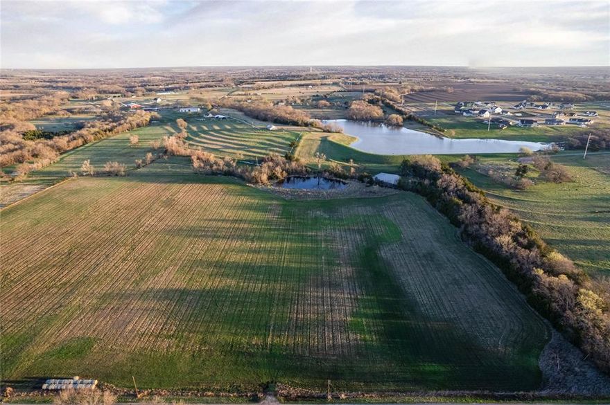 This Collin County property offers more than 20 acres located east of Central Expressway near Anna, Texas, with a mix of open land, water features, and road frontage that may support agricultural, residential, or recreational use, subject to buyer verification and local regulations. The land features generally level topography that may be suitable for a residence, barn, shop, or other improvements, and may also support livestock grazing, hay production, or similar agricultural uses. Two ponds are located on the property and may provide water for livestock or recreational fishing while contributing to wildlife activity and landscape diversity. Access is provided by a county-maintained road with reported water and electricity nearby; buyers should verify availability and connection requirements with utility providers. Road frontage allows for convenient entry and potential driveway placement. A portion of the property includes partial five-strand barbed wire fencing, and additional improvements may be needed depending on intended use. The property may qualify for agricultural valuation; buyers should confirm current status and eligibility with the Collin County Appraisal District. No deed restrictions are reported; buyers should verify all applicable regulations, permitted uses, and development standards. A portion of the property lies within a FEMA 100-year floodplain, which may impact development and insurance; buyers are encouraged to review flood maps and conduct due diligence. Located in Van Alstyne ISD with access to Celina, McKinney, Melissa, and Sherman via Central Expressway. All information is deemed reliable but not guaranteed; buyer and buyer’s agent to verify all information.
