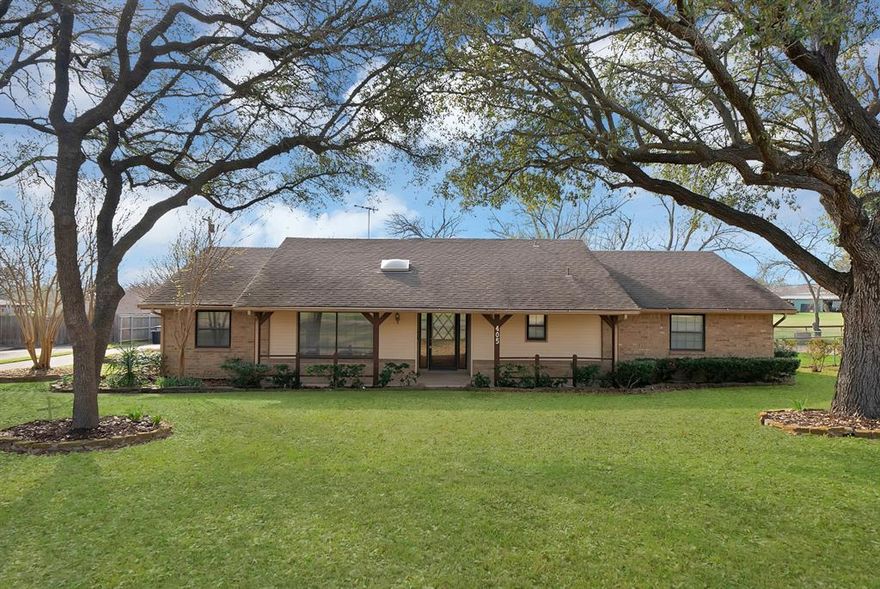 Nestled on a spacious lot in Ovilla and shaded by beautiful mature trees, this well-maintained brick home offers a peaceful setting with plenty of room to spread out both inside and out. Set back from the street with a wide front yard and established landscaping, the property provides a welcoming first impression and a sense of privacy while still being conveniently located near local schools, shopping, and dining. Inside, the home features a functional layout with generous living spaces and timeless character. The main living area is anchored by a striking brick fireplace with raised hearth and wood mantel, creating a warm focal point perfect for gatherings or quiet evenings at home. Large windows allow natural light to fill the space while offering views of the surrounding yard. The kitchen features abundant cabinetry, extensive counter space, and a practical galley-style layout that provides excellent storage and workflow while also offering the opportunity for updates or personalization to match your style. Bedrooms are comfortably sized and the layout offers flexibility for everyday living, guests, or a home office. Step outside to enjoy the large backyard and covered patio, ideal for relaxing, grilling, or entertaining while overlooking the expansive grassy yard with plenty of space for pets, play, gardening, or future outdoor additions. A standout feature of the property is the two separate garages offering parking for up to four vehicles, providing excellent flexibility for vehicles, storage, hobbies, or workshop space. With mature trees, generous outdoor space, and solid construction, this Ovilla property combines the charm of established living with the opportunity to make it your own.