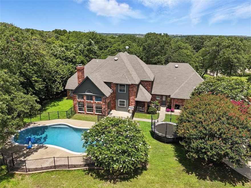 Nestled on a serene, 1.6-acre wooded lot, this custom-built home offers the perfect blend of luxury and functionality. The gated entry and fully fenced perimeter creates a sense of seclusion, while the heavily wooded surroundings provide natural beauty and shade. Home has an open floor plan with soaring ceilings and expansive windows that fill the home with natural light, highlighting the warm tones of the wood floors and the brick wood-burning fireplace that anchors the spacious living room. The chef’s dream kitchen is truly the heart of the home, featuring granite counters, two dishwashers, two ovens, a 36” induction cooktop, a built-in Viking refrigerator, and a second built-in Sub-Zero refrigerator in the laundry room. Whether you're hosting a small gathering or entertaining a crowd, this kitchen will handle it all. Cabinets off the living room even have a fun hidden door feature for kids to explore the closet under the stairs. The home also offers two washer and dryer hookups, perfect for multitasking on busy days. There is a
closed formal dining that is currently being used as a study and is a great flex space to suit your specific needs. Large primary bedroom is downstairs and offers a beautiful bathroom and walk in closet. Retreat outdoors to enjoy the in-ground pool on the large, treed lot. Need a workshop or extra storage? You’ll love the insulated shop with full electric service and backup generator ports—a rare and valuable feature that will assist in keeping the power on if it goes out. The home is equipped with whole-house surge protection and a central vacuum system, ensuring convenience and peace of mind. Home also has a large walk-in attic that could easily be converted in the future to a bonus room. Home is pet friendly and features a custom large dog door. Whether you're enjoying the amenities inside, or relaxing poolside in the shade of towering trees, this home has it all. Don’t miss your chance to own this truly special retreat.