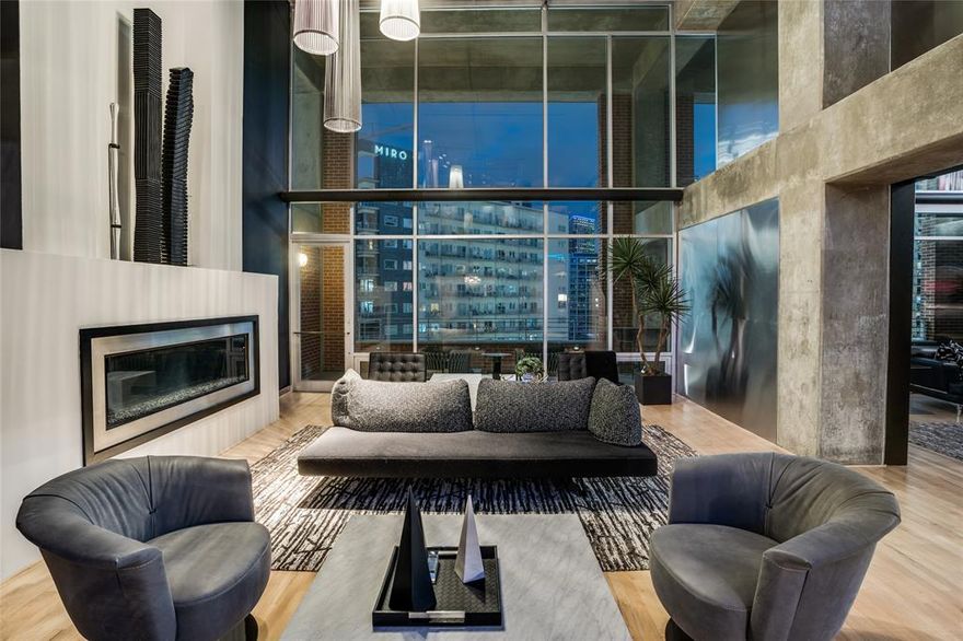 This Uptown contemporary loft condominium delivers-confident, elevated, and unapologetically stylish. With sweeping views of Downtown and Uptown, this two-bedroom, two-and-a-half-bath residence offers architectural edge paired with everyday livability. A rare four dedicated parking spaces further distinguishes the home in one of Dallas’ most walkable and connected neighborhoods.

The open-concept living and dining areas are ideal for entertaining, filled with natural light and framed by skyline views that shift beautifully from day to night. A sleek dry bar anchors the space. Just beyond, the private terrace serves as a true extension of the home, offering rare outdoor living with panoramic city views.

The kitchen, open to the main living space, continues the home’s clean, modern design with durable finishes. Both bedrooms offer a calm retreat featuring high ceilings, expansive windows, and a well-appointed ensuite bath. A dedicated home fitness area completes the residence. Enjoy walkable access to the American Airlines Center, Klyde Warren Park, the Katy Trail, luxury shopping, dining, and the Dallas Arts District—delivering true lock-and-leave living without compromise.