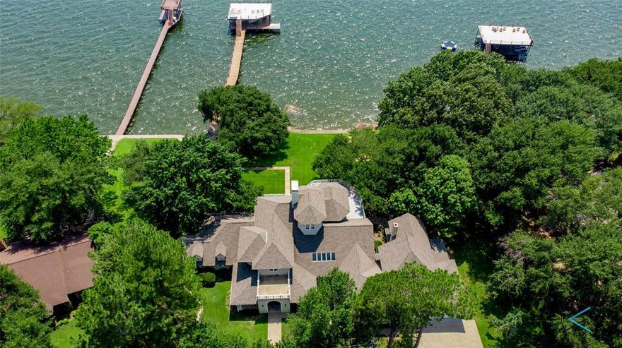 This Coastal inspired home is a landmark on Cedar Creek Lake.  Wonderful Estate setting , mature trees, gorgeous open water and196 feet of shoreline.  Spacious interior with light filled rooms and captivating views at every turn.  High volume ceiling heights, wood floors and plenty of room to gather with two living areas and family game room.  Cooks Kitchen opens to main living , white cabinetry, huge island for eating and serving.  Incredible owners suite with walk out balcony and forever views.  Relax and enjoy the outdoors on the covered porch areas.  Outdoor kitchen with cozy seating around the outdoor fireplace.  Large boathouse is located in deep water, accommodates 2 boats, with additional pwc lifts, and covered sitting area.  Huge party deck is the place to be for the annual Fourth of July Airshow.