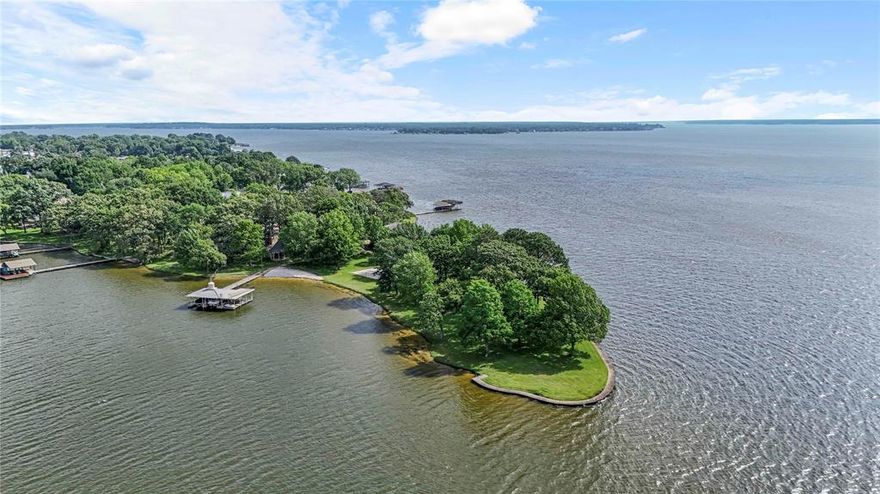 Welcome to one of the most iconic properties on Cedar Creek Lake—a rare, private gated estate situated on an extraordinary peninsula point lot offering 2.44 acres and approximately 1,337 feet of pristine shoreline. This is a once-in-a-generation opportunity for the discerning buyer seeking unmatched privacy, tranquility, and panoramic water views. With both sunrise and sunset exposures and cooling southern breezes off the point, this property offers an idyllic setting for lakeside living. The grounds are built for outdoor enjoyment, featuring a sandy volleyball court, sport court with adjustable basketball goal, a sandy beach, and a charming gazebo. The lot includes 1.10 acres above the 325 line and 1.25 acres below, providing ample space to expand the current home, add a guest house, or build a custom lakefront estate from the ground up. A well-equipped boathouse includes two full slips and lifts for seven personal watercraft, making lake adventures effortless. One of the few true peninsula point lots available on Cedar Creek Lake, this is a legacy property where memories are made and the possibilities are endless.