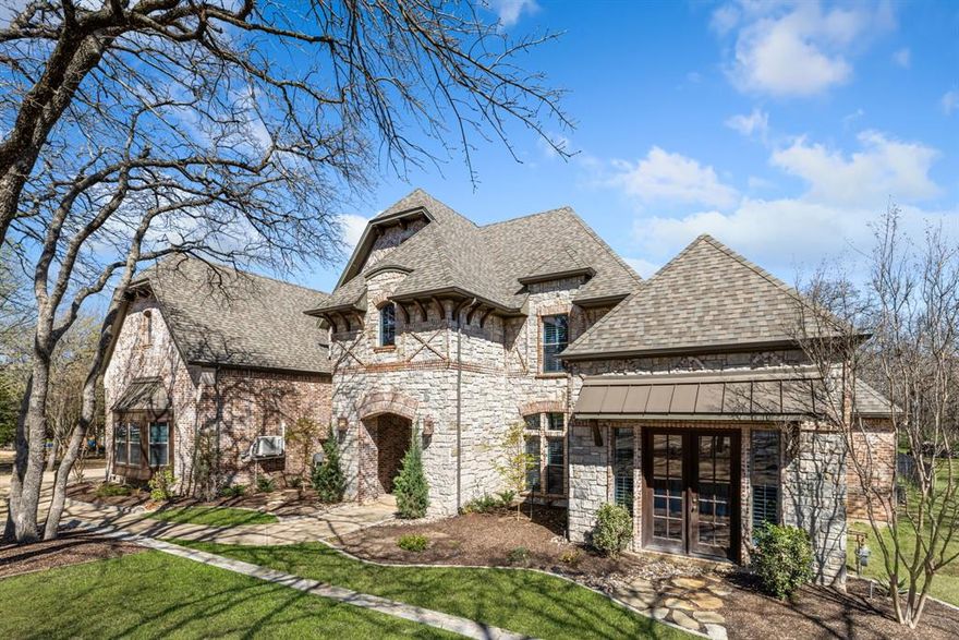 Tucked away on a lush, tree-lined 2.5-acre estate, this exquisite custom home offers the perfect fusion of luxurious resort-style living and everyday practicality. Thoughtfully designed with timeless sophistication, this 5-bedroom residence features ensuite bathrooms for every bedroom, including two lavish primary suites on the main level, providing ultimate flexibility for multigenerational living or distinguished guest accommodations. From the stately approach to the circular drive, the home makes a lasting first impression. An oversized, temperature-controlled 4-car garage with sleek epoxy flooring complements the impressive curb appeal. Inside, the grand foyer welcomes you with soaring ceilings, rich hardwood floors, and graceful architectural detailing that exudes both elegance and warmth. Culinary enthusiasts will be drawn to the gourmet kitchen, outfitted with double islands, double ovens, wine cooler, and a Jenn-Air gas range and Subzero refrigerator —all designed to elevate both everyday living and upscale entertaining. A walk-in butler’s pantry adds a layer of convenience, while the open-concept flows into the spacious family room and creates an inviting ambiance for hosting and relaxation alike. Upstairs and downstairs laundry rooms, extensive built-in storage, plantation shutters, and dual staircases reflect a home designed with both beauty and functionality in mind. Step outside into a private sanctuary where every day feels like a getaway. A heated diving pool with a spa and tranquil water feature anchors the outdoor retreat, complete with a fully-equipped summer kitchen, stone fireplace, and custom landscape lighting to set the mood for evening gatherings or serene solitude. Located in a highly-rated school district and just a short drive from shopping, dining, and major thoroughfares, this exceptional estate offers the rare opportunity to live in relaxed luxury without compromising convenience. This is more than a home—it’s a lifestyle.