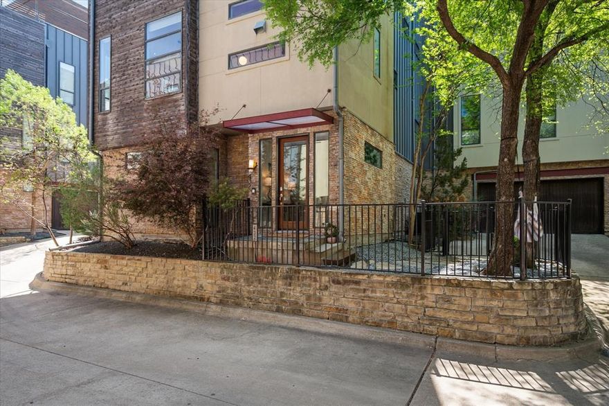 Experience elevated modern urban living in this impeccably remodeled tri-level townhome, ideally positioned between Bishop Arts & Downtown Dallas with rare, unobstructed skyline and Reunion Tower views from an expansive 610 sq ft rooftop deck-perfect for sunrise coffee, sunset cocktails, al fresco dining, entertaining, and front-row seats to spectacular NYE fireworks. A nearly $100K designer renovation (2022) infuses the home with curated modern style, including refinished bamboo hardwoods across all living levels, updated Sonneman and Schoolhouse lighting, & thoughtful upgrades throughout. The first floor welcomes you with a large foyer and a dedicated home office enhanced by dramatic 3D metallic Schumacher wallpaper. The bright & airy main living level features battery-powered shades, built-in surround speakers, abundant natural light, & a refreshed fireplace with striking midcentury modern floating mantle. The beautifully updated kitchen showcases oak cabinetry, Manzoni wood-wave hardware, granite countertops, an expanded pantry, Samsung Bespoke 4-door refrigerator, custom pet-friendly built-in dining nook, and Schumacher wallpaper accents. Both bedrooms offer ensuite bathrooms. The spacious primary suite includes ceiling speakers and a custom closet system, along with a fully reimagined spa-inspired bathroom featuring a skylight, quartz countertops, floor-to-ceiling tile spanning the entire vanity wall, pendant lighting, a freestanding soaking tub, & a large walk-in shower. A third-floor laundry room with custom cabinetry. This prime location offers incredible future value with Harold Simmons Park now under construction—a transformative 250-acre urban nature park along the Trinity River with anticipated access point beside the community. Planned features include scenic trails, playgrounds, nature preserves, waterfront amenities, gathering areas, and innovative outdoor experiences that will significantly enhance the lifestyle and vibrancy of the surrounding area.