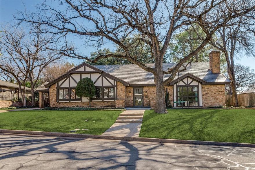 This exceptional Tudor-style residence blends timeless Old-World elegance with thoughtful design, refined architectural details, and generous living spaces, further enhanced by a Class 4 hail-resistant roof offering superior durability and long-term peace of mind. A Porte Cochere and gated driveway lead to a rear-entry garage, creating a private and sophisticated arrival.
Inside, a grand slate-floored foyer sets the tone for the home’s craftsmanship and character. Formal living and dining rooms showcase rich wood flooring and leaded glass windows, while the living room is anchored by an impressive, oversized fireplace that is perfect for elegant entertaining. The dining room ceiling features a striking Art Deco inspired motif, adding a layer of architectural sophistication.
The inviting family room offers a second wood-burning fireplace, beautifully accented by a dramatic copper overmantel. A step-up leads to the chef’s kitchen, appointed with stainless steel appliances, double ovens, a pantry, and a statement copper hood above the island cooktop. The expansive breakfast room features a graceful, curved wall of windows, filling the space with natural light and offering tranquil views of the surrounding landscape.
The main level includes a spacious and private guest suite with an ensuite bath, ideal for visitors or multi-generational living. The oversized primary retreat is a true sanctuary, featuring an ensuite bath with separate tub and shower, an expansive closet, and custom built-ins.
Upstairs, two generously sized bedrooms share a Jack-and-Jill bath with double vanity. A 7x29 balcony overlooks the wooded backyard, providing a serene outdoor escape and completing this distinctive home where classic charm meets enduring quality.