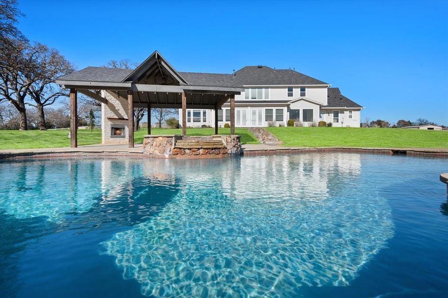 This home screams “Since you’ve been gone!” Key features is two primary suites! Built in 2008 and set on just under five private acres, this exceptional four-bedroom, six-bath estate offers the perfect blend of luxury, recreation, and peaceful country living—just minutes from city conveniences. Outside city limits and surrounded by open space, the property delivers rare privacy with no close neighbors and breathtaking views overlooking a picturesque Arabian horse ranch. Designed for both relaxation and entertainment, the grounds feel like a private resort. Enjoy a sparkling swimming pool complete with a slide and cabana, plus a lighted sand volleyball court, pickleball court, and basketball court—ideal for hosting gatherings or staying active at home. Equestrian amenities include a horse barn, while a detached workshop provides ample space for hobbies, storage, or business needs. Inside, the home has been thoughtfully updated with refreshed countertops, fresh interior paint, and modern light fixtures. Spacious living areas and well-appointed bedrooms offer comfort and functionality, while large windows frame sweeping views of the surrounding landscape. This one-of-a-kind property delivers a relaxing, resort-style atmosphere with the charm of the countryside—without sacrificing proximity to shopping, dining, and everyday city needs. A truly unique opportunity to enjoy space, views, and lifestyle all in one remarkable setting.