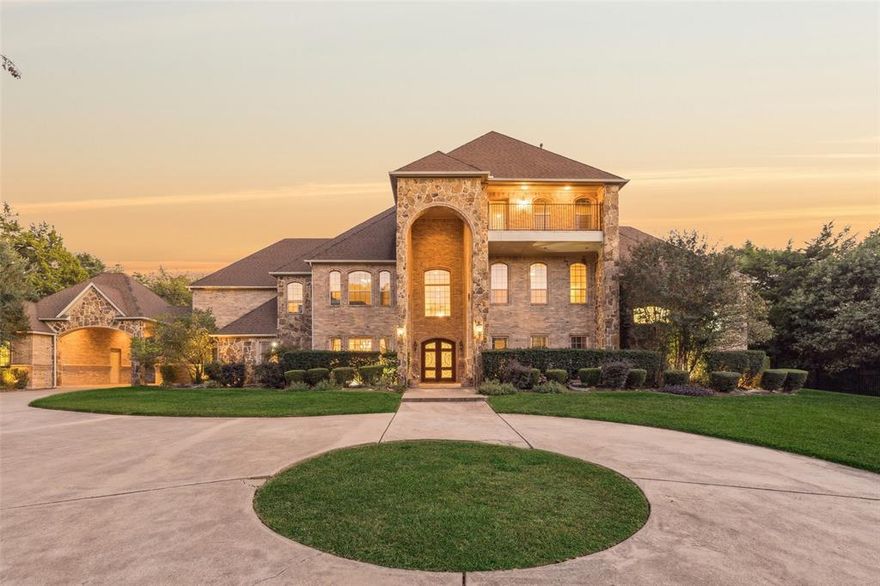 Experience the pinnacle of luxury living in this immaculate custom estate, perfectly situated in a gated community with panoramic views of Joe Pool Lake and the DFW skyline from the stunning third-story balcony. This one-of-a-kind residence maintained by its original owners is masterfully designed for both grand entertaining and everyday comfort. A circle drive and a stunning brick and stone elevation lead to a grand entry showcasing a dramatic staircase and a formal dining room crowned by a showstopping chandelier and elegant wainscoting. The chef’s kitchen is a true masterpiece, featuring a large island, wrap-around breakfast bar, granite countertops, two sinks, stainless steel appliances, an abundance of cabinetry & a WI pantry w-an adjacent coffee bar. The living room features a wet bar, perfect for effortless entertaining. A private study with coffered ceilings and rich wood paneling provides the ideal space for work or reflection. The massive primary suite is a serene retreat with a cozy fireplace, sitting area, coffee bar, spa-like bath with a walk-in shower, and French doors opening to an oversized patio overlooking the tranquil, tree-lined property. New HVAC downstairs & the upstairs unit is under a year old! The second floor offers an impressive media and game room with a wet bar, reading nook, and pool table area, while the third floor presents a flexible living or entertainment space with a balcony showcasing breathtaking lake views. Each bedroom features a private ensuite bath, ensuring comfort and privacy for all. Additional highlights include four living areas, two fireplaces, two staircases, a designated game room, elevator shaft prepped for a lift, and a driveway perfect for a sport court. The expansive double patios provide the perfect backdrop for entertaining or relaxing in complete seclusion on over two acres surrounded by mature trees. This home is a true masterpiece, crafted for those who desire sophistication, privacy, and unparalleled views.