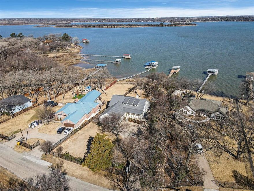 Experience refined lakefront living on nearly one acre of prime waterfront with private dock and lift, designed for both full time enjoyment and the ultimate weekend escape. This custom luxury home, built by a highly respected builder, blends craftsmanship, comfort, and panoramic open water views.  Inside, you will find three bedrooms and three and a half baths, all enhanced by beautiful wood flooring and thoughtful architectural detail. The gourmet kitchen is a showpiece, featuring marble countertops, commercial grade gas cooktop, double ovens, and abundant workspace for effortless entertaining. Expansive windows frame the lake and flood the open concept living, dining, and kitchen areas with natural light, creating a seamless indoor outdoor experience.  The owner’s suite is a private retreat with a custom closet, dual vanities, and a luxurious soaking tub. A secondary downstairs bedroom with ensuite bath offers ideal privacy for guests. Upstairs, a spacious second living area includes a beverage bar and beverage refrigerator, along with a large bunk room complete with built in double bunks and a full bath, perfect for hosting family and friends.  An oversized garage provides generous storage for vehicles and lake toys. Step outside to a large covered porch with outdoor kitchen and grill area, ideal for sunset dinners and relaxed gatherings. The private boat dock with lift offers direct access to open water and endless days on the lake.  If you have been searching for exceptional waterfront living with space, quality, and unforgettable views, this property delivers. Schedule your private showing today and start living the lake life you have been dreaming about.