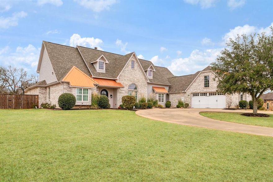 Built in 2015, this beautiful modern contemporary home is located in Stone Ridge Estates and sits on over 1.6 acres. A concrete circular drive enhances curb appeal and provides ample space for gardening, recreation, or the addition of a pool. The home offers five bedrooms—plus a media-game room—along with four full bathrooms, 3 fireplaces, formal living and dining rooms, and an open-concept kitchen, dining, and family room ideal for entertaining. The custom kitchen offers stainless appliances including refrigerator and trash compactor, custom cabinets, center work island, gas cooktop, double oven, and warming drawer. Additional features include a built-in dining booth, tall ceilings and crown molding throughout. The primary suite features a sitting area with built-in cabinetry, sink, and refrigerator, as well as an ensuite bath with a separate shower, jetted tub, dual vanities, and an oversized walk-in closet. Outdoor amenities include a screened-in porch, wood deck, and a 20x40 metal shop suitable for ATVs or a boat. This custom home offers exceptional space and versatility for a variety of lifestyle needs.