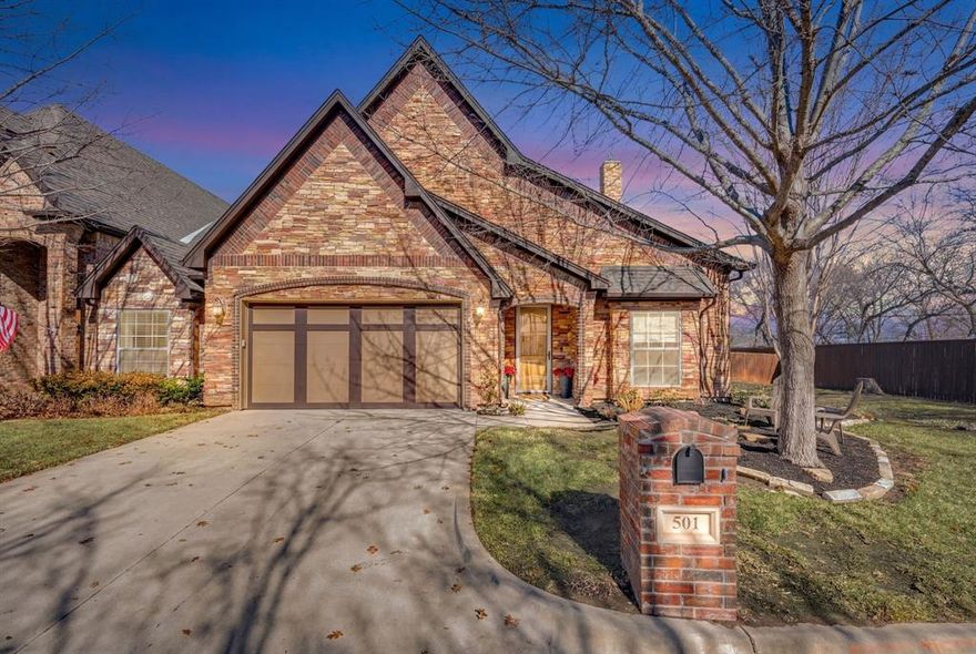 Tucked away at the end of a private drive in the heart of Grapevine’s coveted historic district, this beautifully crafted single-story home offers rare privacy paired with timeless curb appeal. A striking brick and stone façade, arched architectural details, and a welcoming front entry set the tone for the quality and care found throughout the home. Inside, recently refreshed designer paint and natural light enhance the spacious open-concept layout, creating an inviting atmosphere ideal for both everyday living and entertaining. Wide-plank flooring flows through the main living areas, while tray ceilings, and a cozy fireplace add warmth and character. The expansive living and dining spaces easily accommodate gatherings large or small. The gourmet kitchen serves as the true centerpiece of the home, featuring a large center island, gas cooktop, double ovens, ample cabinetry, generous counter space, and a walk-in pantry that must be seen to be appreciated. The kitchen opens seamlessly to the main living area, offering both functionality and connection. Enjoy the dining room space large enough to accomodate a table of all sizes. The private primary suite is a relaxing retreat with room for a sitting area and serene backyard views. The ensuite bath includes a spacious vanity, walk-in shower, and an oversized walk-in closet with custom shelving. Two additional bedrooms provide flexibility for guests, a home office, or hobby space. Enjoy effortless indoor-outdoor living under the covered patio overlooking a fenced backyard—perfect for morning coffee, evening relaxation, or entertaining. With lawn care and exterior maintenance included through the HOA, this lock-and-leave lifestyle offers exceptional convenience.