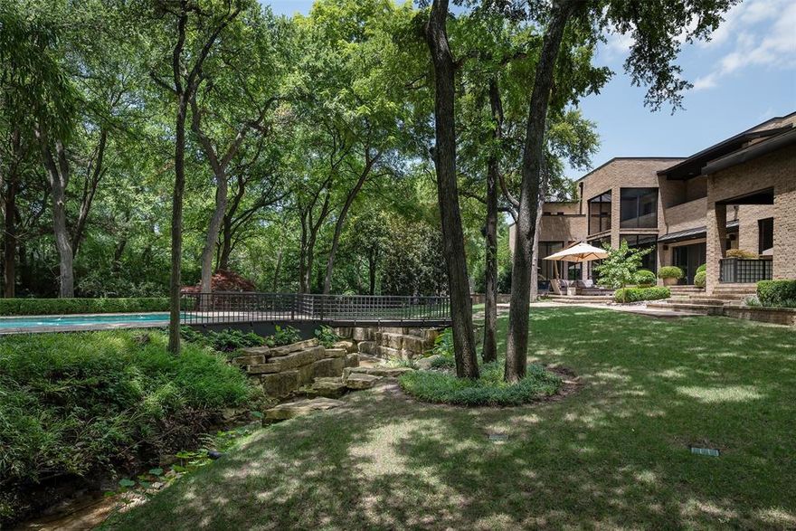 This stylish and contemporary home in Preston Hollow is a true oasis, offering a peaceful retreat on a beautiful lot. Built in 1985 and meticulously remodeled twice, first in 1998 and again in 2008, this 4 bedroom residence boasts 6.1 baths, & spans an impressive 7,144 sqft. Property is surrounded by lush landscaping by Bonick Landscaping. Inside, every room is beautifully appointed with finishes curated by designer Rick Rozas. The living room boasts a stunning 90-year-old burning bush mahogany crotch wood & Danby marble fireplace, adding warmth & elegance. The chef’s kitchen is equipped with top-of-the-line appliances. In addition to the main living areas, the home includes a media room-gym, a safe room, a study, & three guest bedrooms, each with luxurious finishes. The primary suite is a serene escape, complete with a fireplace and a spacious bath featuring multiple walk-in closets. Outside, the property features a koi pond, a seating area, and a heated saltwater swimming pool.