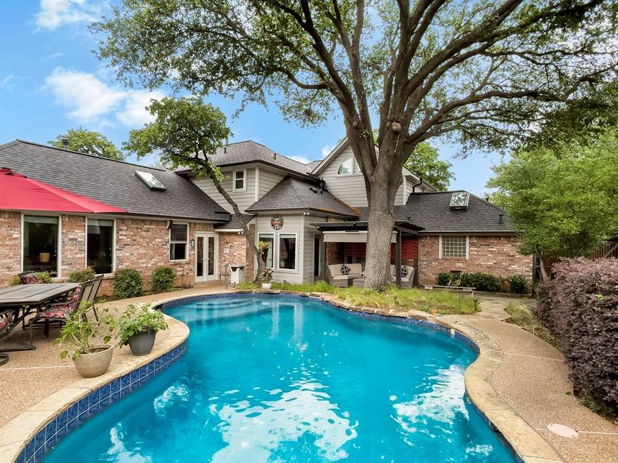 Situated on a private, tree filled corner lot in Grapevine, this beautifully designed split level home offers exceptional indoor and outdoor living with standout curb appeal. The inviting front entrance welcomes you in, while the garage is tucked away on the lowest level and positioned to the side for a clean exterior presence.

The true centerpiece is the expansive outdoor living space designed for relaxation and entertaining. Surrounded by mature trees, the backyard feels like a secluded retreat. A saltwater pool with diving board anchors the space, complemented by a pergola, cozy firepit seating area, and a large outdoor dining area.

Inside, an open concept layout flows from the front living area with a wood burning fireplace into the dining room with a built in buffet and serving hatch to the kitchen. The kitchen features a large gas cooktop framed in brick, double ovens, a generous eat in island, and a functional U shaped layout. Tucked behind the kitchen and above the garage, the family room offers a private retreat with a wet bar and fridge, along with direct access to the two car garage and utility room. The utility room includes a sink and added storage. 

The primary suite includes a spa like ensuite with double sinks, vanity area, jetted tub, and a large walk in shower. Downstairs also features a private office with its own bath and outdoor access. Upstairs offers a loft overlooking the living area, along with two bedrooms and a full bath. All bathrooms complete with updates.

Blending privacy, character, and resort style amenities, this one of a kind home is a must see.
