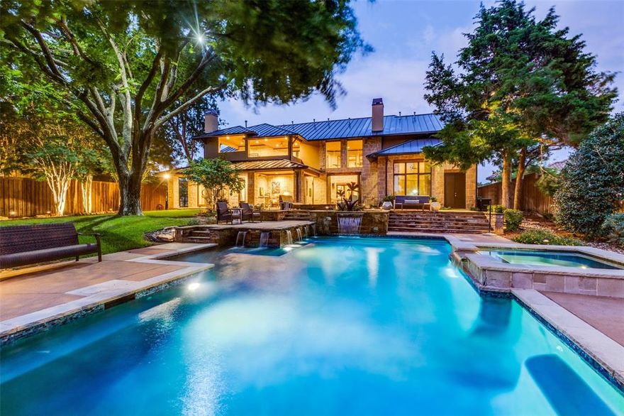 Step into a world where architecture meets art – where every element of this striking three-level residence feels curated for both serenity and statement. Perched in a private gated enclave beside 400+ acres of parkland, the home is a bold blend of natural stone, smooth stucco, and sleek metal rooflines that harmonize with its elevated setting. Inside, soaring 20-foot ceilings, warm hickory floors, and exposed steel beams set a tone that’s both modern and grounded. Brick-accented walls and rich hardwood ceilings create a sense of depth and texture, while expansive Pella windows flood the home with natural light. An elevator seamlessly connects all levels, from the entertainment-focused main floor to the upper level’s lofted bedroom suites and the 3,145 SF garage below – engineered into the hillside, giving hidden, straight-in access for 8+ vehicles. Every space has been designed for effortless livability, luxurious entertaining, and quiet moments alike. The kitchen is a showpiece, anchored by a natural wood island, Viking appliances, and a dramatic 20-ft brick wall, with a 16-foot scullery keeping prep and clutter out of sight. The wet bar rivals that of a boutique hotel, complete with SubZero wine storage, a Hoshizaki ice maker, dual refrigerator drawers, a drawer-style dishwasher, and a pass-through window to the loggia. The Primary Suite feels like a private sanctuary, with 14-ft wood ceilings, an oversized custom closet, and a hidden pocket door to the study. Outside, the backyard is a true destination: a sleek pool and spa, oversized stone fire pit, and an air-conditioned loggia with 20-ft ceilings, two TVs, gas fireplace, and steel shutters – designed for year-round enjoyment. More than a home, this is a lifestyle – sophisticated, immersive, and unforgettable.