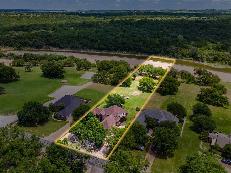 Discover riverfront living at its best at 7502 Ravenswood Road in the gated community of Pecan Plantation. Nestled on nearly 2 acres along the Brazos River, this 4-bedroom, 3-bath home offers both privacy and a true connection to nature. Stroll through lush gardens, enjoy al fresco dining with sweeping river views, or launch a kayak for a peaceful paddle right from your backyard. Inside, an open foyer leads to the main living area, where a dramatic wall of windows, soaring vaulted ceilings, and a striking two-story brick fireplace set the stage for gatherings. The chef’s kitchen is designed to impress with double ovens, gas cooktop, dual sinks, prep island, and breakfast bar. A formal dining area and cozy breakfast room provide multiple dining options. The main-level primary suite is a private retreat with an updated ensuite featuring dual vanities, an oversized shower, and private patio access. A flexible second bedroom on the main level doubles as a home office, while upstairs offers two additional bedrooms plus a versatile flex space. With a new roof in 2024, resort-style amenities in Pecan Plantation, and an unbeatable riverfront setting, this property is more than a home—it’s a lifestyle. Schedule your private tour today and experience it for yourself!