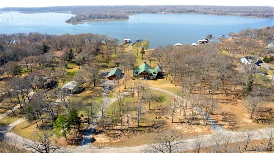 Welcome to an exceptional Lake Fork waterfront estate located at 788 RS County Road 3500 in Emory, Texas, nestled within the highly desirable Northshores community on the west side of Lake Fork. This established waterfront neighborhood is known for its natural beauty, abundant wildlife—including deer, raccoons, and armadillos—and convenient access from the DFW Metroplex. This impressive 4,108 square foot custom home offers 4 bedrooms and 3.5 bathrooms, blending rustic charm with grand architectural design. Inside, you’ll find a striking hand-carved log staircase, a massive great room with cathedral ceilings, a wood-burning fireplace, and expansive picture windows that frame breathtaking lake views and fill the home with natural light. Outdoor living is unmatched, featuring a spacious entertainment area complete with an outdoor kitchen and fireplace—perfect for hosting family and friends year-round. Waterfront amenities include a two-slip boathouse, private boat ramp, and concrete retaining wall, providing effortless lake access for boating and fishing enthusiasts. Adding even more value is a detached two-car garage with a new 815 square foot living addition. This versatile space is ideal for guest quarters or entertaining and includes a mini kitchen, full bathroom, pool table area, and an upstairs bedroom. Located just minutes from Emory, this rare Lake Fork property combines luxury, privacy, and convenience—making it an ideal full-time residence, weekend retreat, or investment opportunity on one of Texas’ premier fishing lakes.