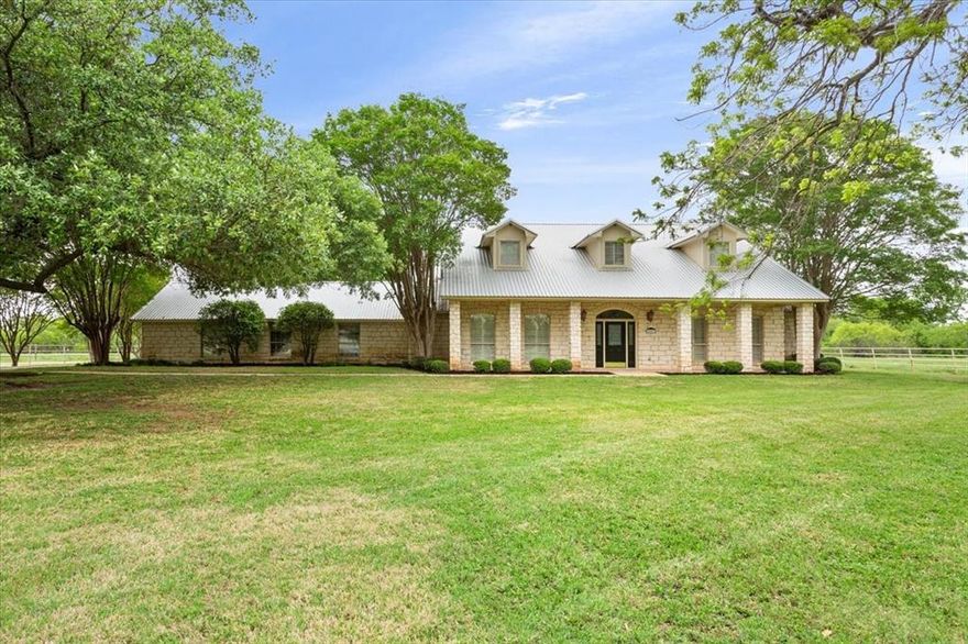 The whole package!!  This lovely ranch-style home sits on 84+ acres of prime grazing pasture with a workshop, livestock barn, and two large tanks.  Nestled back in the trees just off of Loop 340, the location alone is a dream, combining the convenience of town with the tranquility of the county.  From the second you turn into the gated, crepe myrtle-line driveway, you'll know you've found your forever home.  Built with love from the ground up, the floor plan is designed to perfection.  You'll step inside and be welcomed by the formal dining, and your wow-factor will go into over-drive when you see the tall ceiling in the living room.  The kitchen and breakfast area is a cook's greatest vision, unfolding right before your eyes. There's an isolated, primary suite that you'll never want to leave.  With added space for a sitting area, or home office, as well as a door directly to the back porch and a massive walk-in closet, they've spared no expense.  Step down the hallway, and after you see the half bath and utility room, you can walk through the garage directly into the heated and cooled extra space, which could be a fourth bedroom or even an office, game room, or home gym.  Upstairs, there's two more bedrooms and another full bath, with a view that money can't buy.  Build your dreams here when you can step out back directly into the pasture.  With two large stock tanks, plenty of shade and mature trees, and a fantastic open pasture, we've bundled it all up in one pretty package.  Bring your dreams; leave with a smile.  You just found HOME.