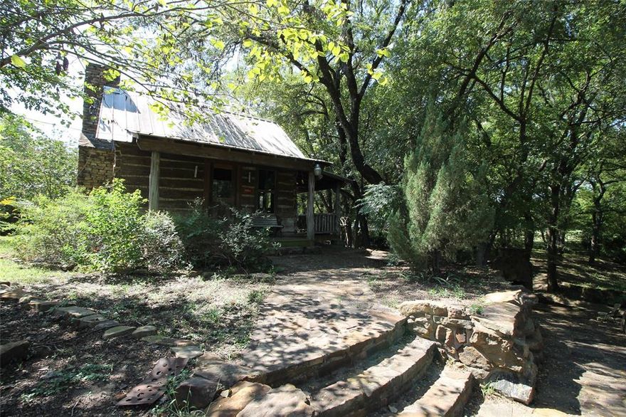 Seize a rare opportunity to own a 34-acre getaway in the heart of Argyle’s Horse Country. This extraordinary property blends rustic charm with modern luxury, offering a serene escape just 30 minutes from DFW Airport. A gated entrance ensures privacy and security, enhancing the exclusivity of this secluded retreat. At its heart is a 1900s style log cabin surrounded by large trees, rolling pastures, picturesque views, just steps from the banks of Hickory Creek, teeming with fish and waiting for anglers to reel in a big bass. The 1900s style log cabin is thoughtfully updated to combine timeless character with contemporary comforts. Inside, discover slate floors, granite kitchen countertops, central AC, and an indoor tree fort that kids will love—perfect for a camping-like experience at home. Property offers a barn providing additional storage and an apartment, for guests or caretakers, while RV travelers will appreciate their dedicated RV site. Equestrian or Livestock? Your animals will be spoiled by the expansive, fenced pasture. Thrill-seekers can explore the rolling terrain on 4-wheelers or dirt bikes, carving trails through pastures and woods, or paddle Hickory Creek by kayak or canoe yards from your doorstep. Whether you dream of a private family retreat, a working ranch, or a weekend getaway, this versatile canvas offers endless possibilities. Bring your dreams and plan your future on this rare gem in Argyle Horse Country! Conveniently located just 18 minutes from the nearest Super Walmart, Whole Foods and the Shops of Highland Village. 30 minutes from DFW Airport and minutes from shopping dining and major roadways. NOTE: This property does not offer a practical building site. The majority of the land sits within a floodplain, and any future development would face significant challenges related to elevation, engineering, and permitting. Constructing habitable or insurable structures here would be complex and costly, making it more of a recreational “toy”.