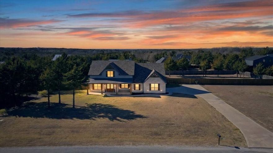 Welcome to your private oasis at 341 Guy Lane, Pottsboro, TX a stunning one-acre custom home offering peaceful luxury in a prime location just minutes from Lake Texoma & championship golf! This distinctively designed residence greets you w timeless brick & stone accents, complemented by a welcoming front porch perfect for relaxing evenings. Step inside to discover soaring beamed ceilings & a seamless open-concept layout that effortlessly blends style & functionality. The heart of the home is the gourmet kitchen, featuring an oversized eat-in island, 42-inch cabinets, designer granite countertops, tumbled stone backsplash & premium stainless steel appliances, plus a massive dining area & a super-sized pantry for all your storage needs.
A thoughtful split bedroom floor plan provides privacy, w two secondary bedrooms & a full bath on one side. The luxurious primary suite occupies its own wing, boasting a massive custom closet & additional storage. The spa-like primary bathroom is a true retreat, featuring a freestanding tub, expansive walk-in shower & modern LED mirror w built-in TV.  Upstairs recent addition is huge 2nd primary bedroom w its own full bathroom ideal for guests, multi-generational living, or a private retreat. Stylish barn doors & ceiling fans throughout add to the home's sophisticated charm. Outside, entertain in style on the expansive extended covered patio complete w a newer hot tub, overlooking a beautifully treed Texas-sized yard. A new underground storm shelter provides peace of mind. Side swing the oversized 2-car garage includes a convenient sink. Laundry rm is conveniently by primary suite, has plenty of cabinets, counter space, a sink & nearby mudroom. This home is Nestled in a wonderful neighborhood close to everything & is perfect for bringing all your toys boats, ATVs & more w easy access to Lake Texoma adventures & golf right down the road. Don't miss this rare opportunity to own a truly special custom home! Schedule private showing!